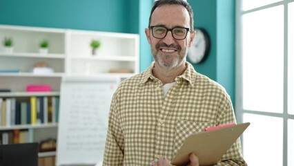 Sticker - Middle age man teacher smiling confident holding clipboard at classroom