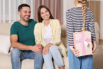 Canvas Print - Little girl presenting her parents with gift at home