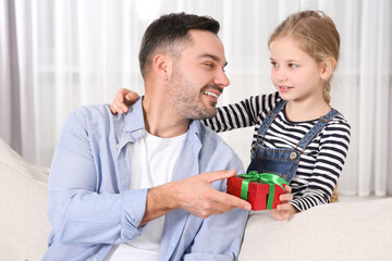 Canvas Print - Cute little girl presenting her father with gift at home