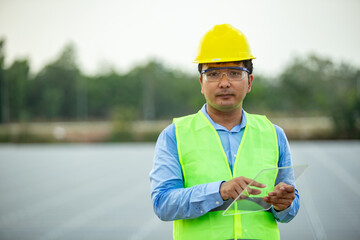 Professional man engineer looking away with pleasure smile while working at ecological green field with solar panels. Photovoltaic power station concept