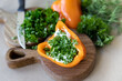 © Guzel - On a wooden board lies bright pepper with filling and chopped greens