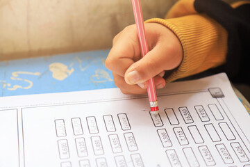 Close up photo of kid hand doing math test on paper in learning activity in classroom