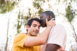© unai - Lgbt concept, couple of multiethnic men in a park kissing each other on the forehead, romantic pose