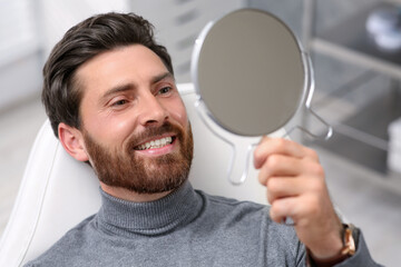 Sticker - Man looking at his new dental implants in mirror indoors