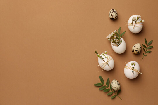 Wall Mural - Happy Easter. Festive composition with eggs and floral decor on brown background, flat lay. Space for text.