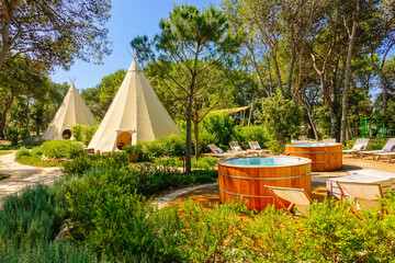 an outdoor relaxation area with teepee tents surrounded by lush vegetation. croatia, europe.
