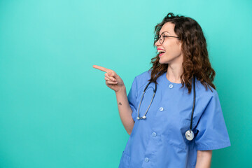 Wall Mural - Young nurse caucasian woman isolated on blue background pointing finger to the side and presenting a product