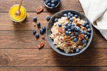 Wall Mural - Oatmeal Bowl, Oat Porridge with Blueberry and Pecans in a Bowl on Rustic Background, Healthy Snack or Breakfast