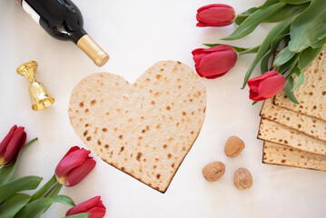 Wall Mural - Matzah shape of heart with red tulips, bottle of wine and walnut on white background. Traditional of  Holiday on Passover. Home symbol of lovely Jewish family in pesach. top view. 