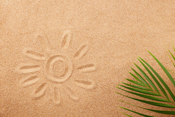 Wall Mural - The sun is painted on the sand and a palm leaf. Sand texture, natural background. View from above.