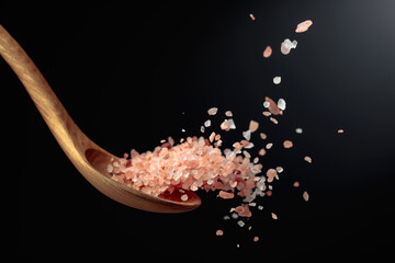 Pink Himalayan salt is poured with a wooden spoon.