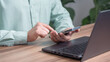 © ParinPIX - Male hand using a smartphone while working on computer laptop at office for investment analyzing company financial report balance with mobile phone. Concept of people are working with mobile devices.