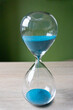 Hourglass with azure sand on wood 