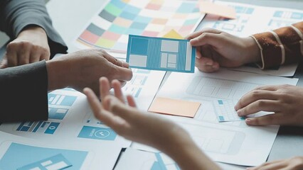 Close up ux developer and ui designer brainstorming about mobile app interface wireframe design on table with customer breif and color code at modern office.Creative digital development agency