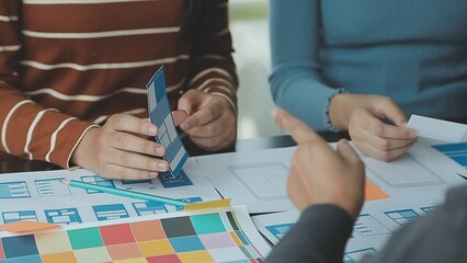 Close up ux developer and ui designer brainstorming about mobile app interface wireframe design on table with customer breif and color code at modern office.Creative digital development agency