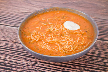 Sticker - Tomato soup with noodles and a spoonful of cream on a wooden background