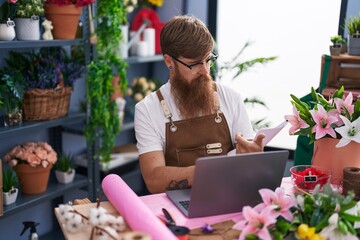 Poster - Young redhead man florist using laptop reading document at flower shop