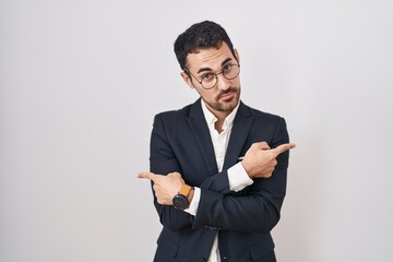 Poster - Handsome business hispanic man standing over white background pointing to both sides with fingers, different direction disagree