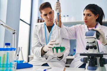 Wall Mural - Man and woman scientists partners using pipette at laboratory