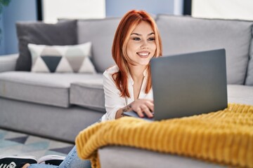 Poster - Young caucasian woman using laptop sitting on floor at home