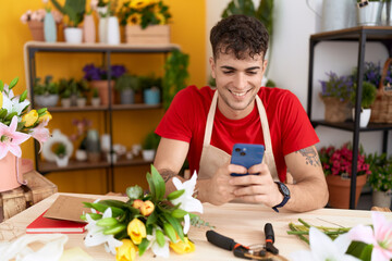 Poster - Young hispanic man florist smiling confident using smartphone at flower shop