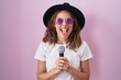Beautiful brunette woman singing song using microphone sticking tongue out happy with funny expression.