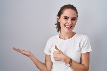 Sticker - Beautiful brunette woman standing over isolated background showing palm hand and doing ok gesture with thumbs up, smiling happy and cheerful