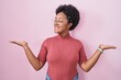 © Krakenimages.com - Beautiful african woman with curly hair standing over pink background smiling showing both hands open palms, presenting and advertising comparison and balance