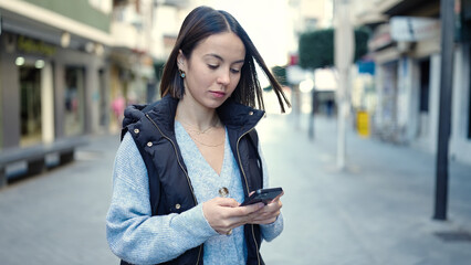 Canvas Print - Young beautiful hispanic woman using smartphone with serious expression at street