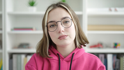 Poster - Young blonde woman student standing with relaxed expression at library university