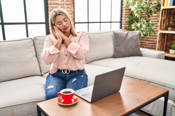 Poster - Young hispanic woman using laptop sitting on the sofa at home sleeping tired dreaming and posing with hands together while smiling with closed eyes.