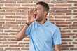 © Krakenimages.com - Brazilian young man standing over brick wall shouting and screaming loud to side with hand on mouth. communication concept.