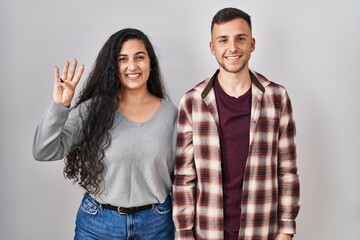 Poster - Young hispanic couple standing over white background showing and pointing up with fingers number four while smiling confident and happy.