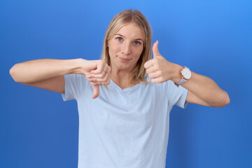 Poster - Young caucasian woman wearing casual blue t shirt doing thumbs up and down, disagreement and agreement expression. crazy conflict