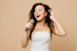 © ViDi Studio - Happy beautiful young woman bride wear wedding dress posing sing song in microphone at karaoke club isolated on plain pastel light beige background studio portrait. Ceremony celebration party concept.