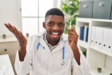 Poster - African american doctor man holding eye drops celebrating achievement with happy smile and winner expression with raised hand