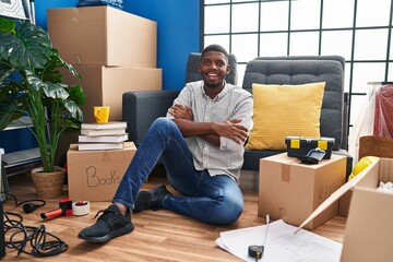 Canvas Print - African american man sitting on the floor at new home happy face smiling with crossed arms looking at the camera. positive person.