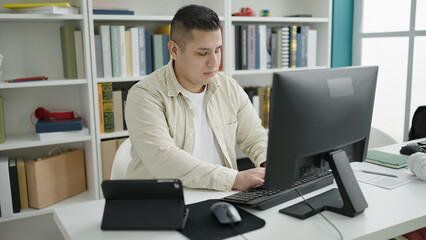 Sticker - Young hispanic man student using computer and touchpad studying at library university