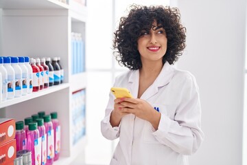 Poster - Young middle east woman pharmacist smiling confident using smartphone at pharmacy