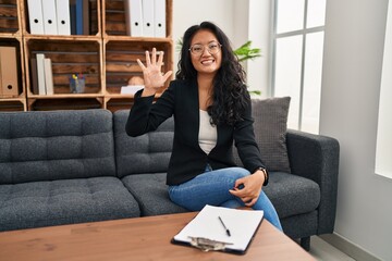 Canvas Print - Young asian woman at consultation office showing and pointing up with fingers number five while smiling confident and happy.