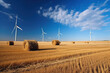 Large metal wind turbines in a rolling stubble field with chinook arc and blue sky