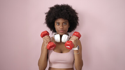 Sticker - African american woman using dumbbells training over isolated pink background