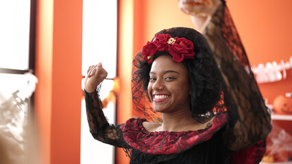 Canvas Print - African american woman wearing katrina costume having halloween party at home