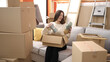 © Krakenimages.com - Young beautiful hispanic woman smiling confident unpacking cardboard box at new home