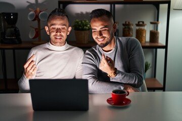 Poster - Homosexual couple using computer laptop beckoning come here gesture with hand inviting welcoming happy and smiling