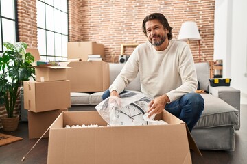 Wall Mural - Middle age man smiling confident unpacking cardboard box at new home