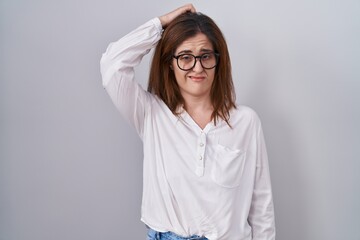 Poster - Brunette woman standing over white isolated background confuse and wondering about question. uncertain with doubt, thinking with hand on head. pensive concept.