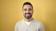 © Krakenimages.com - Young hispanic man smiling confident standing over isolated yellow background