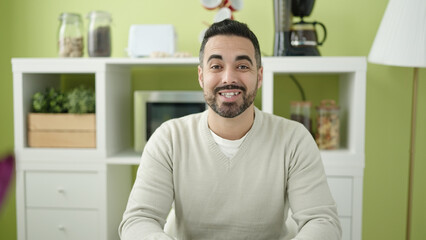 Sticker - Young hispanic man smiling confident sitting on table at home