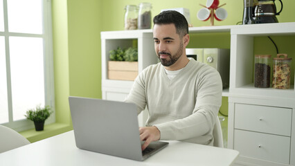 Canvas Print - Young hispanic man using laptop sitting on table at home